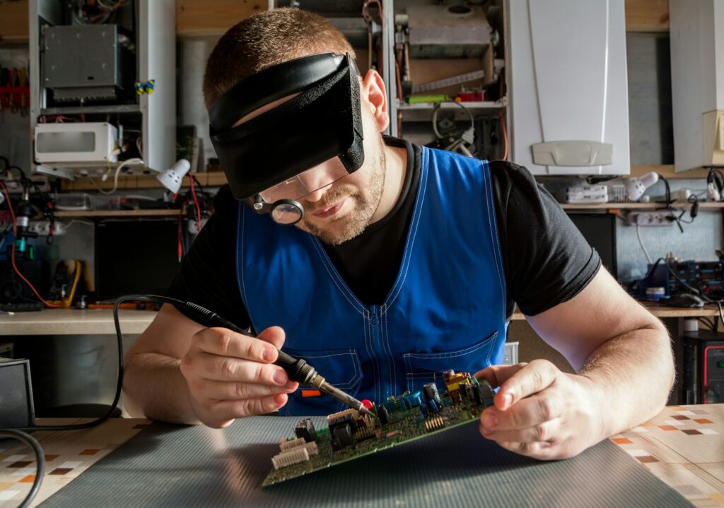 Photo by Bermix Studio a man wearing a blindfold working on a circuit board